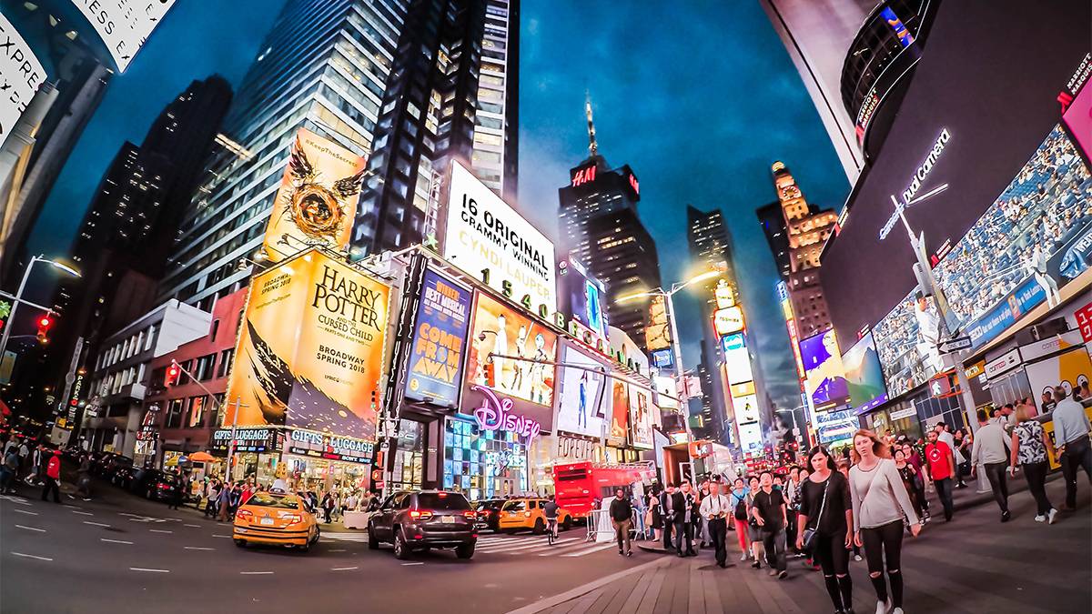 street view of times square at night with taxi cab and people walking along the streets in NYC, New York, USA